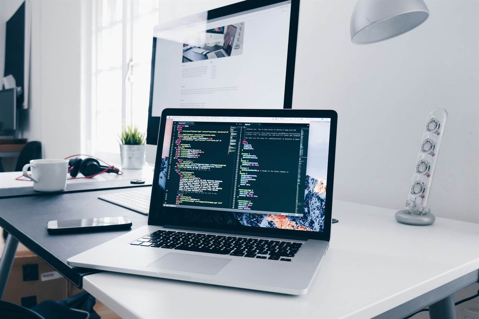 Professional services planning and development workspace with a coded website layout on screen